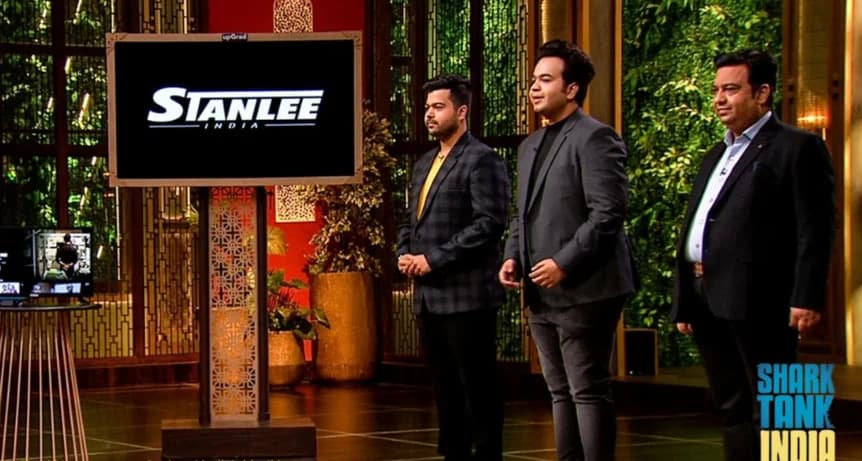 Amar Kant, Nimit and Mayank Luthra on the Shark Tank India stage, the Stanlee India mark on the screen beside them